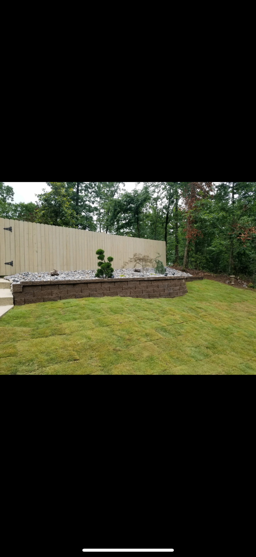 Finished block retaining wall with decorative rock bed and lawn