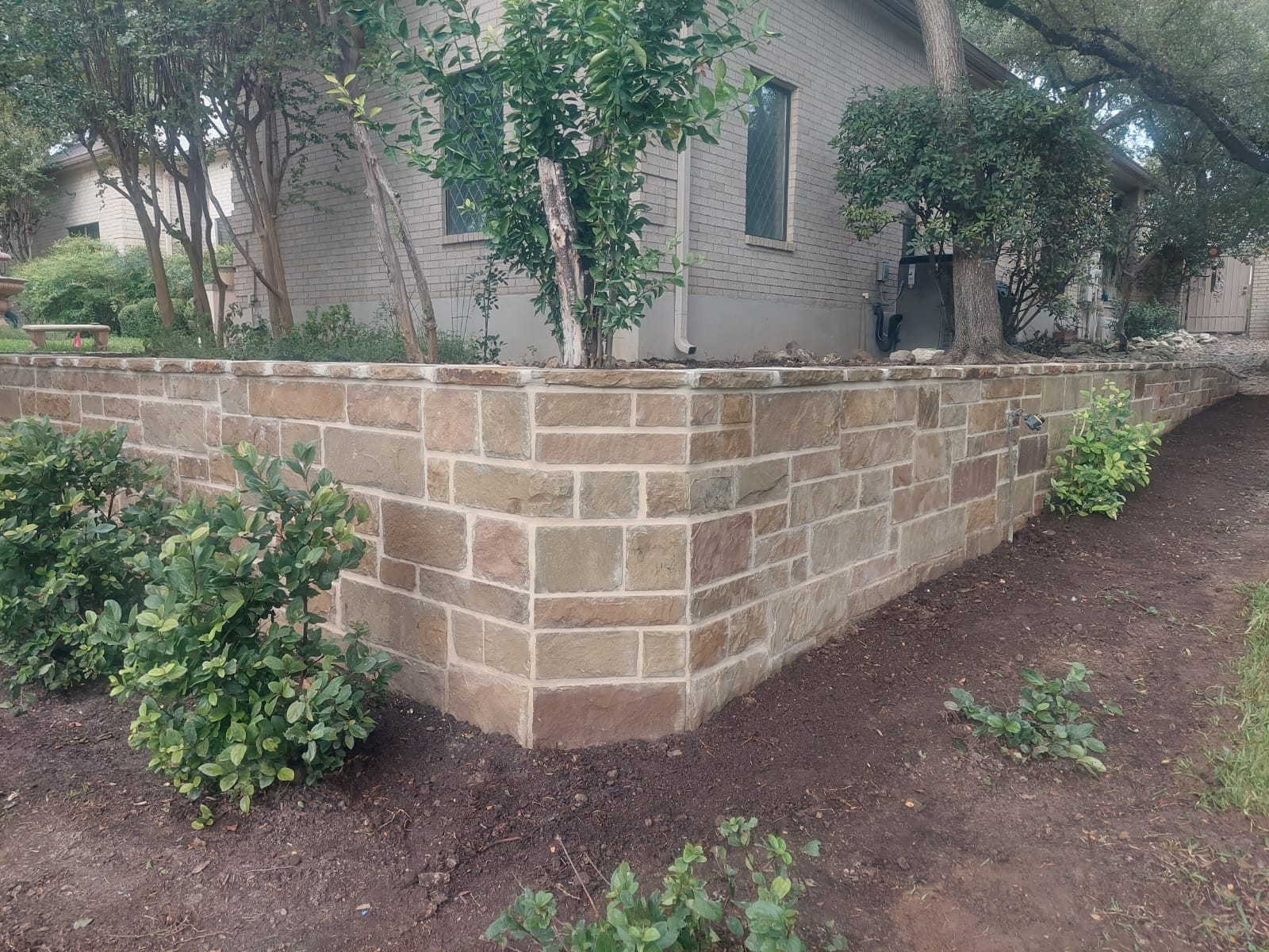 Stone-faced retaining wall surrounding mature landscaping