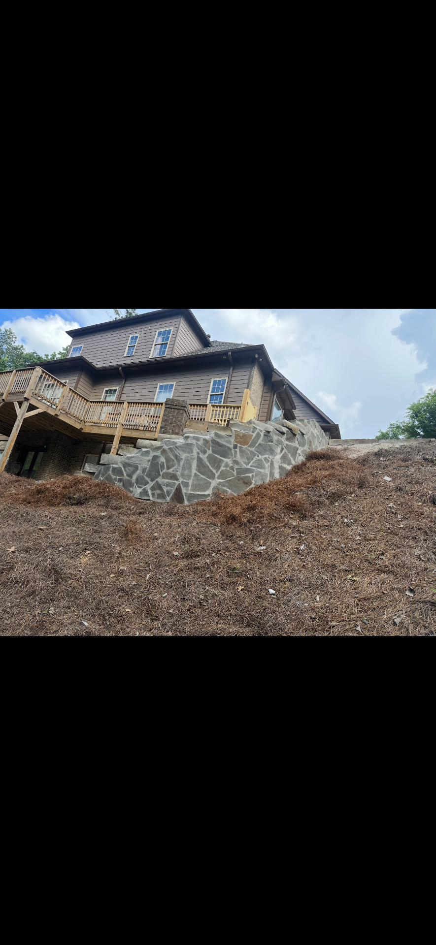 Custom natural stone retaining wall below a deck on a hillside