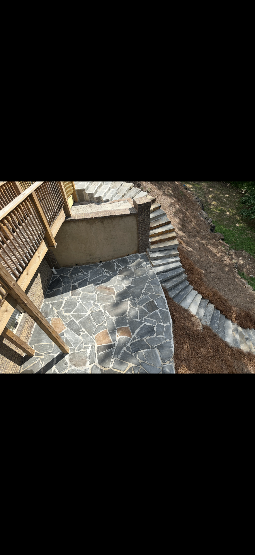 Long outdoor stair run and stone patio integrated into a hillside project