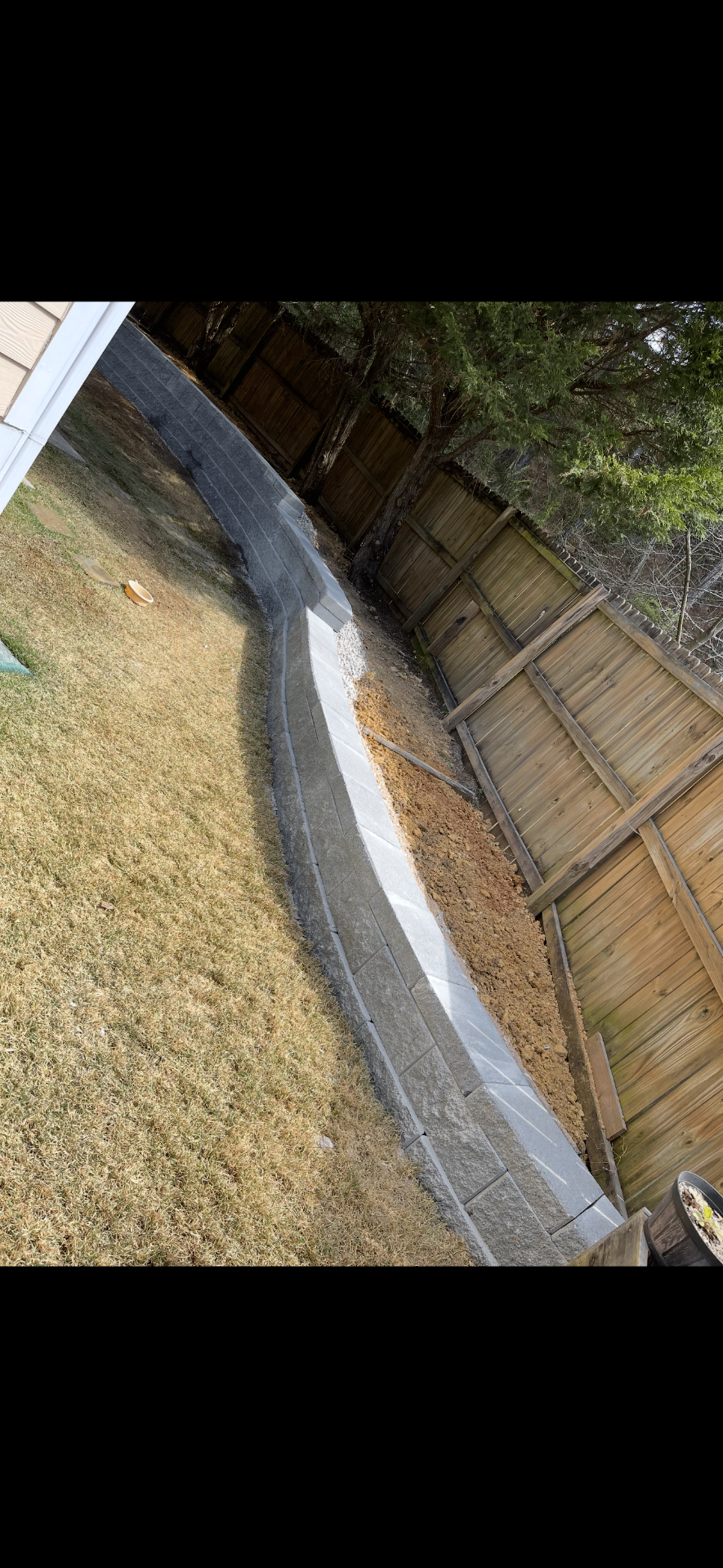 Long engineered retaining wall following a backyard slope